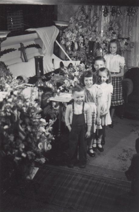 Smiling children beside an open coffin