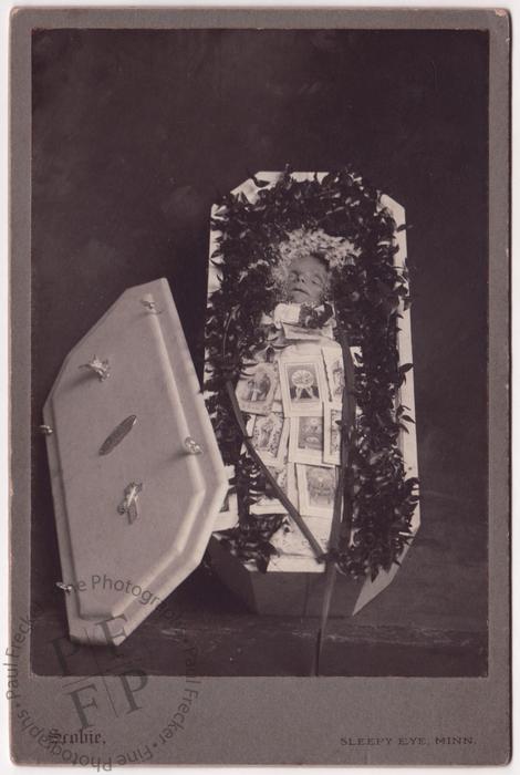 Baby and prayer cards in an open coffin