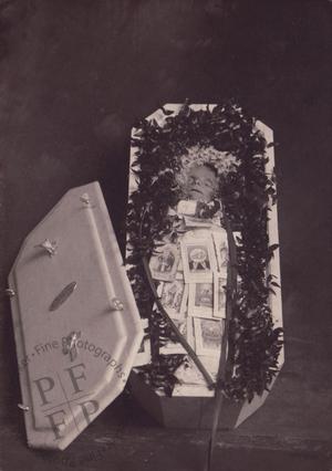 Baby and prayer cards in an open coffin