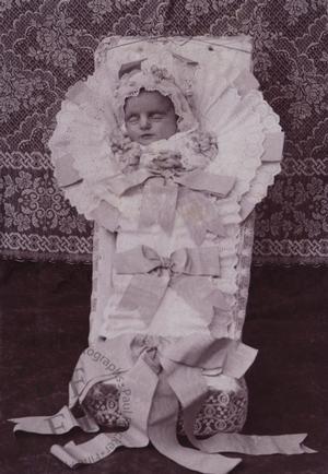 Baby in a coffin with ribbons