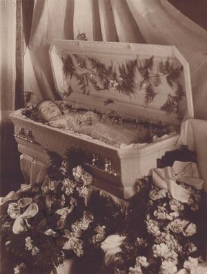 Baby in a white casket with flowers and ferns